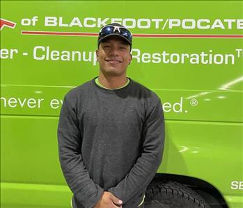 Male employee in black sweatshirt in front of green van