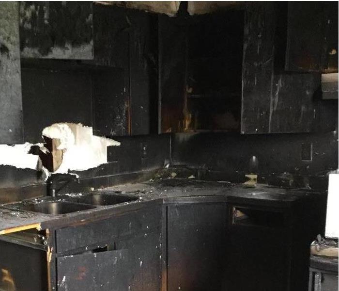 Kitchen suffered severe fire damage. All the walls and counters are black with fire and smoke damage. 
