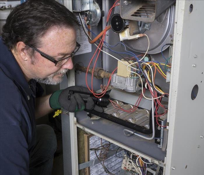 Image of a worker performing maintenance on a furnace