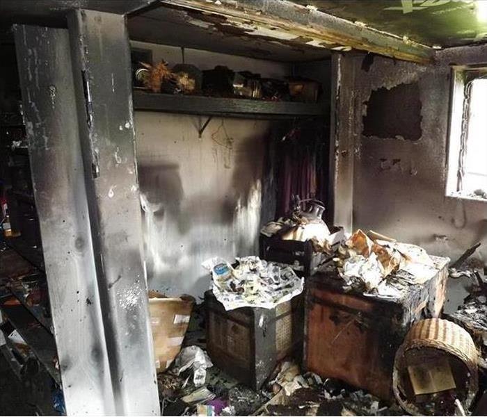 Image of a room with severe smoke and soot damage after a fire. The walls, doors, ceiling and materials are covered with soot
