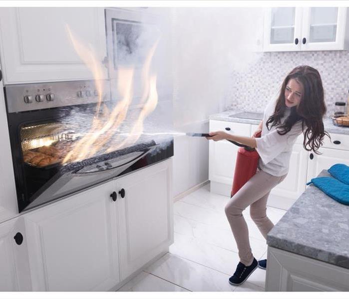 Woman in a kitchen using a fire extinguisher to put out a fire in the oven while cooking croissants.  
